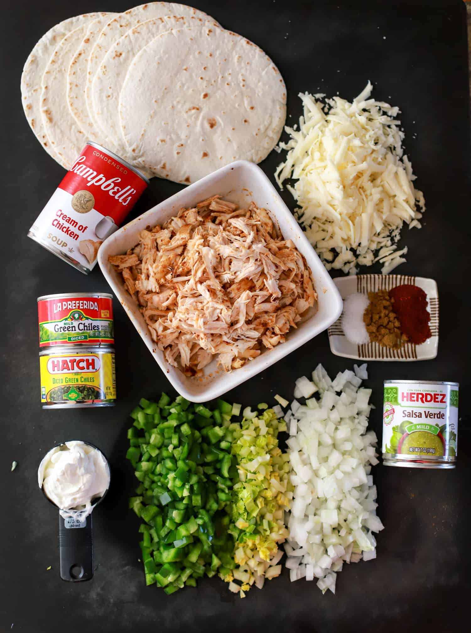 Ingredients for green chicken enchiladas on black board.