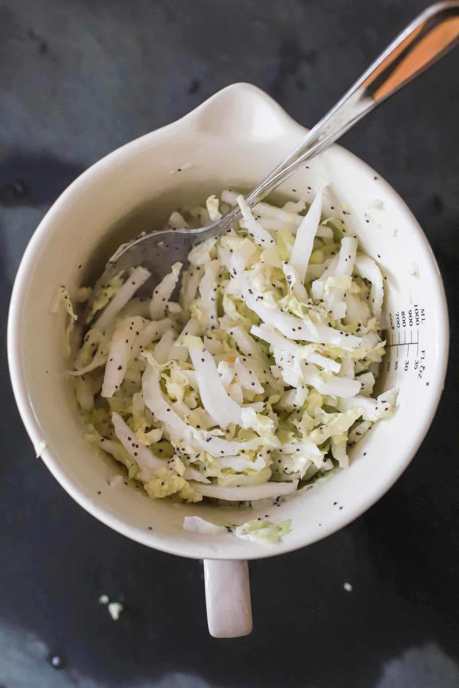 slaw with silver spoon in white bowl.
