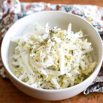 white bowl of greek yogurt slaw topped with poppyseeds ready to be served.