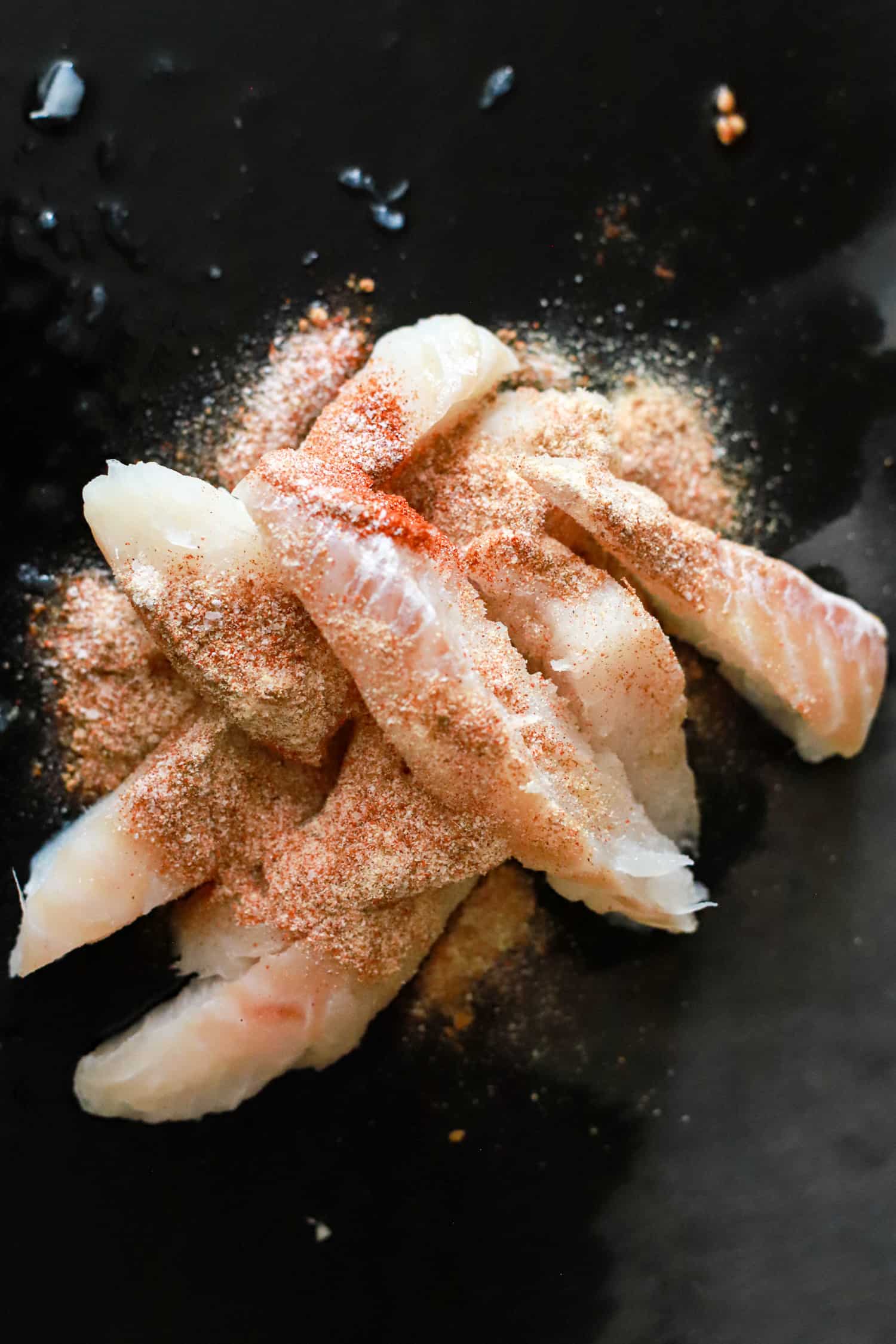 fish pieces with seasoning on a black board.