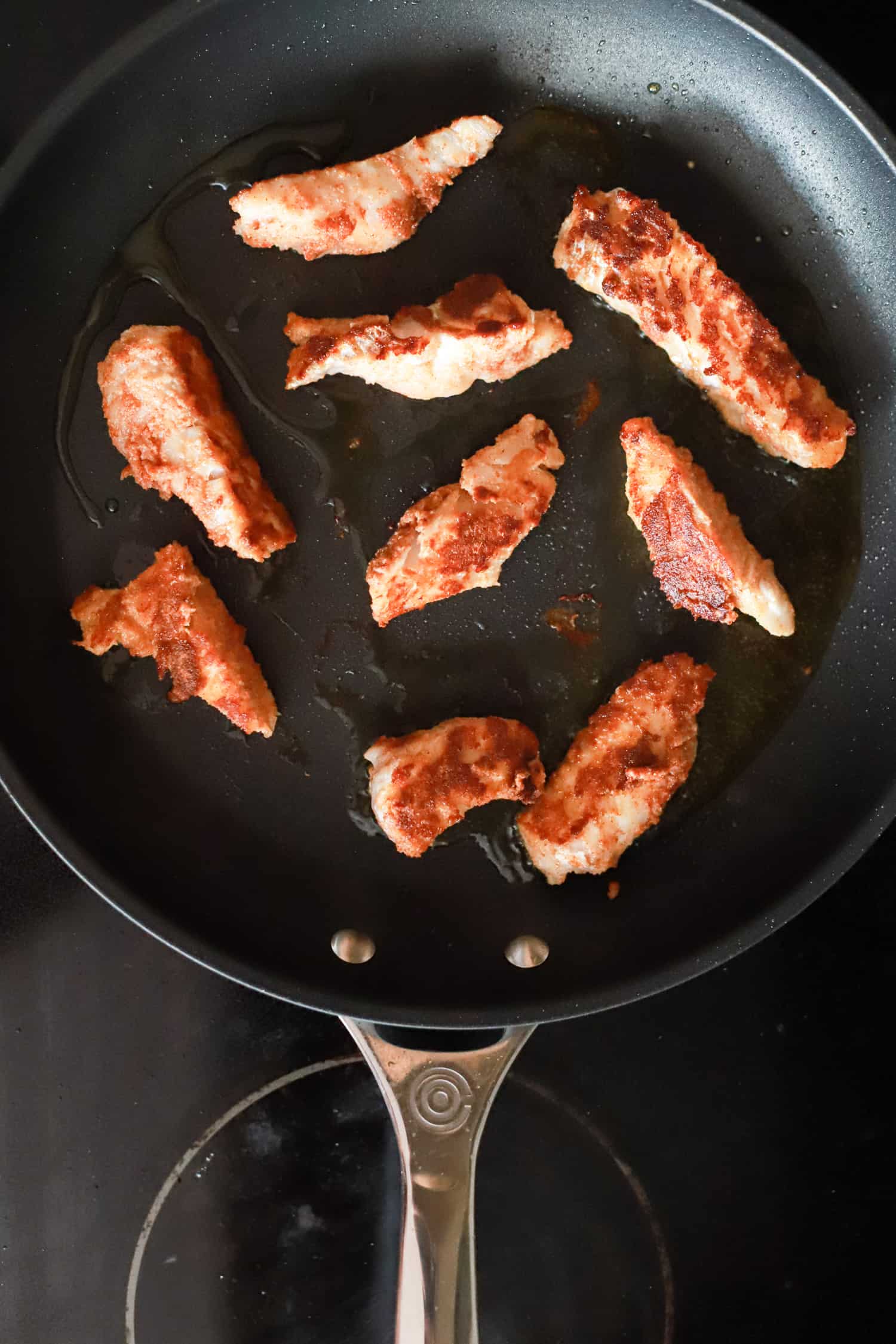 blackened fish pieces cooked in a nonstick skillet.