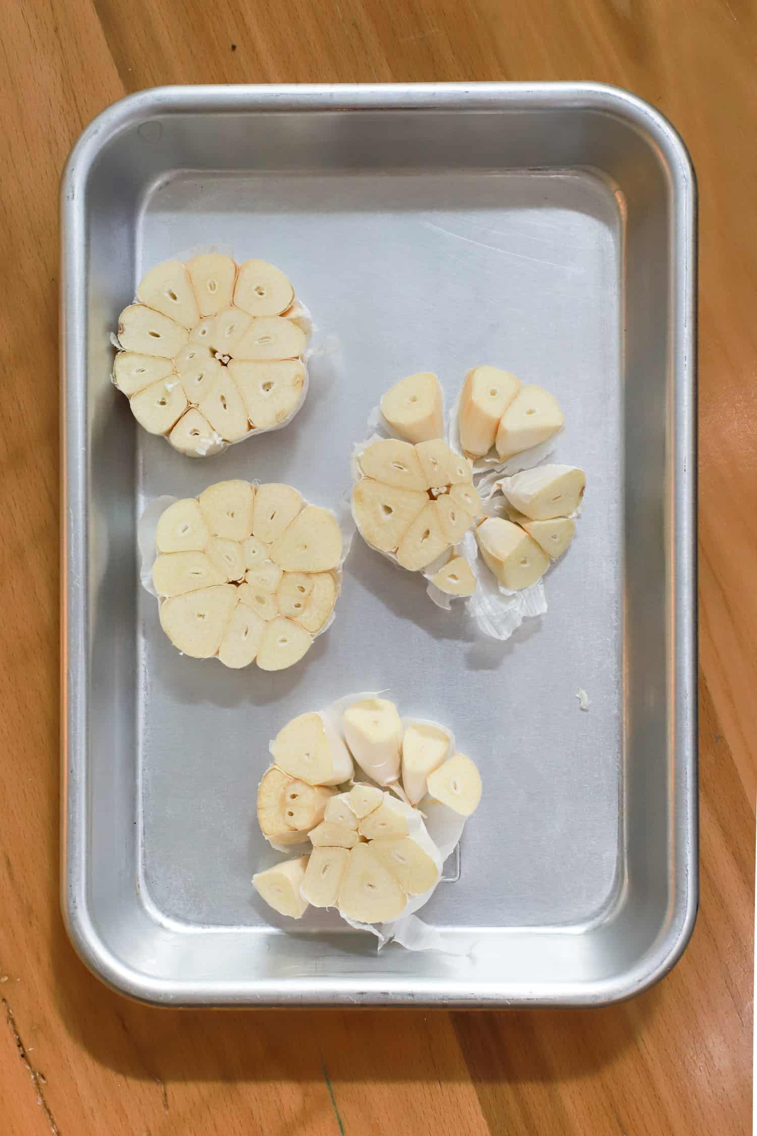 raw heads of garlic cut in half on small baking sheet.