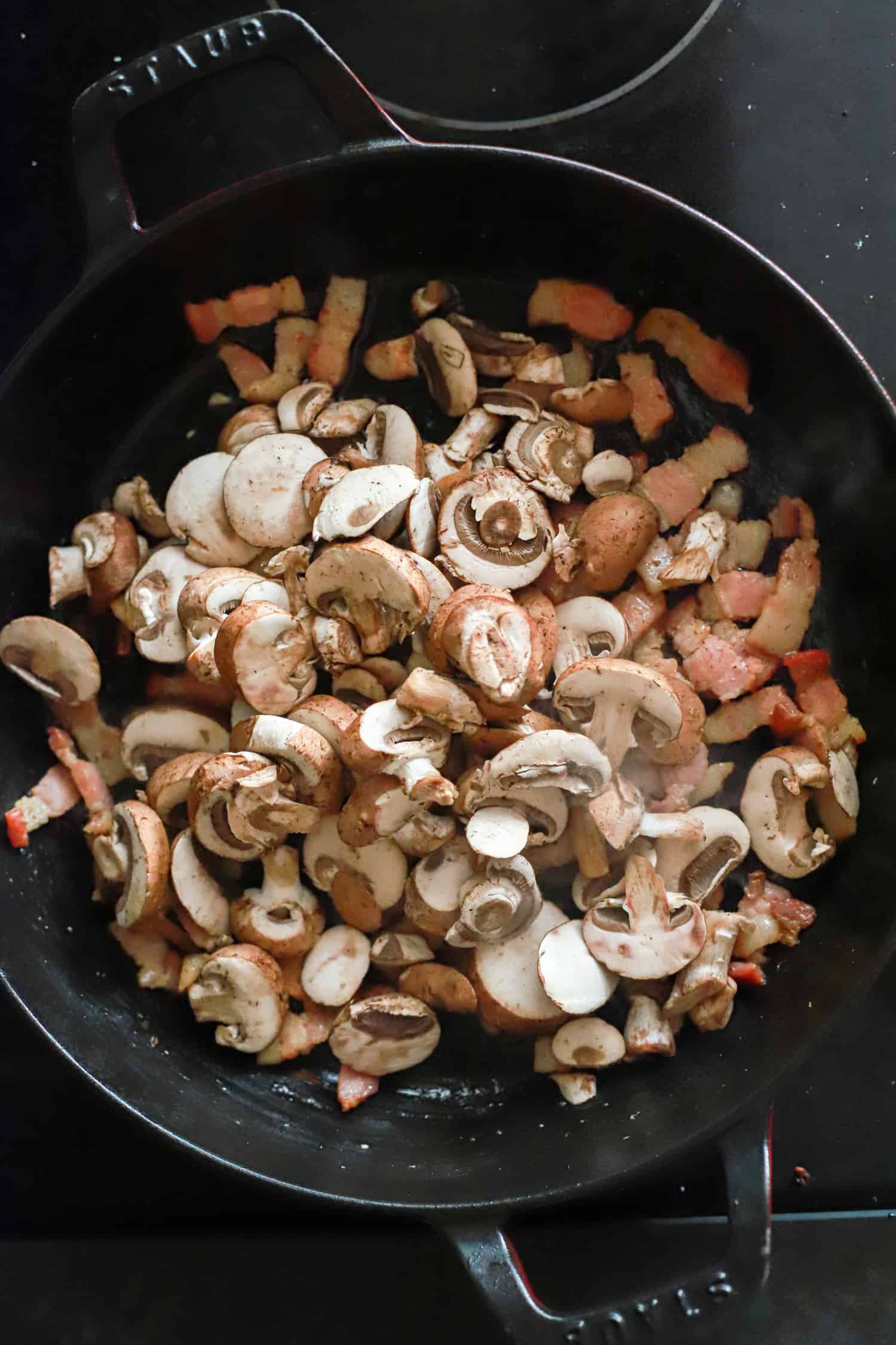 black skillet with raw mushrooms.