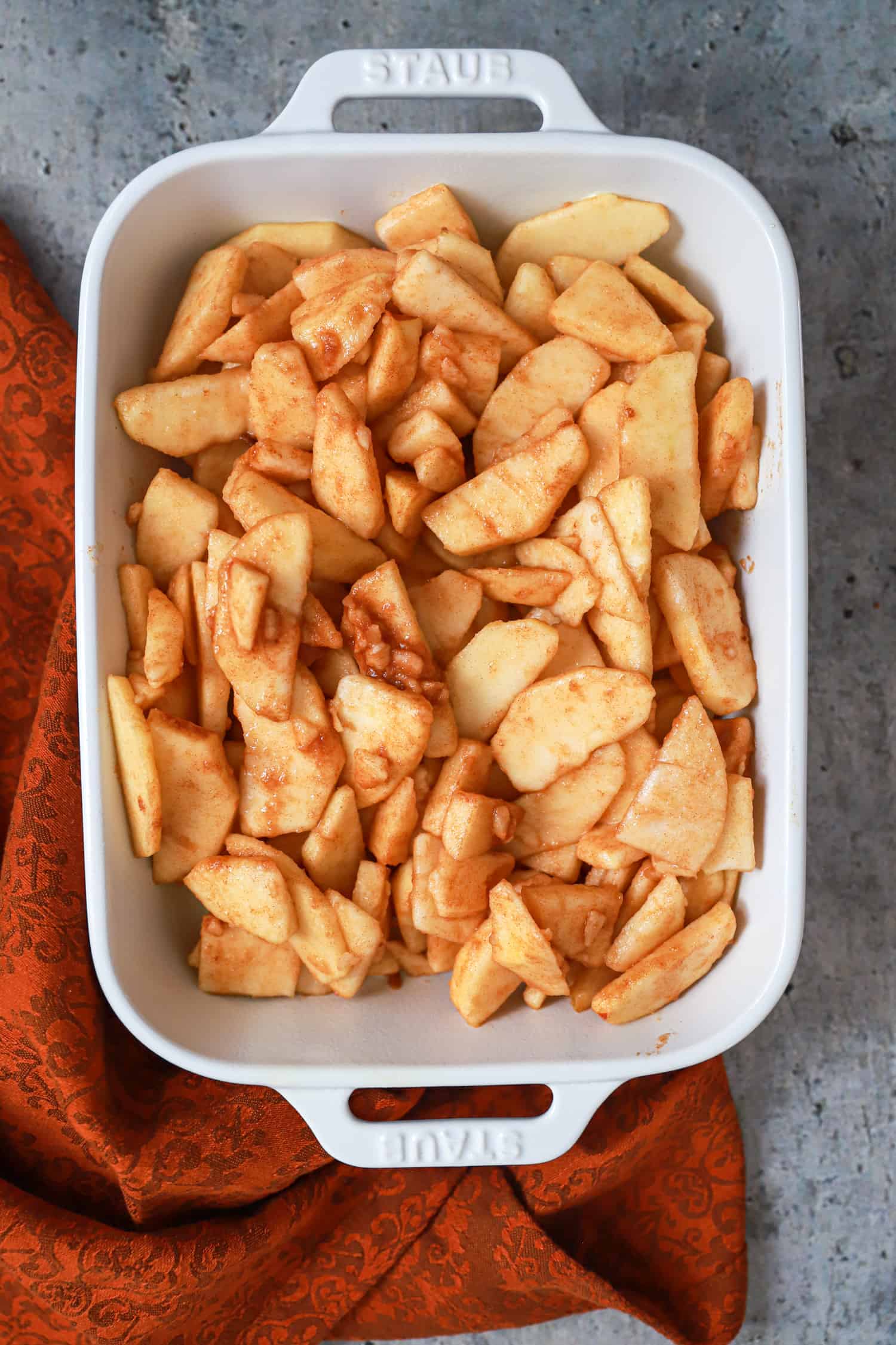 white baking dish with apples ready to be baked into apple crisp.