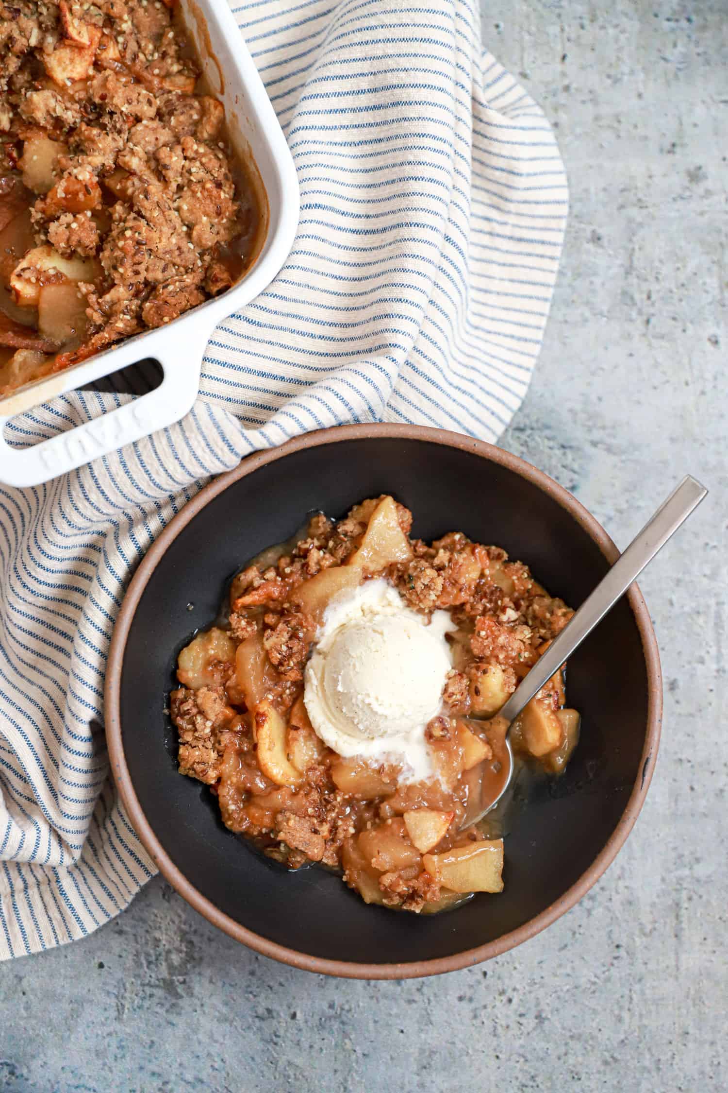 bowl of no oatmeal apple crisp with melting ice cream in the center.