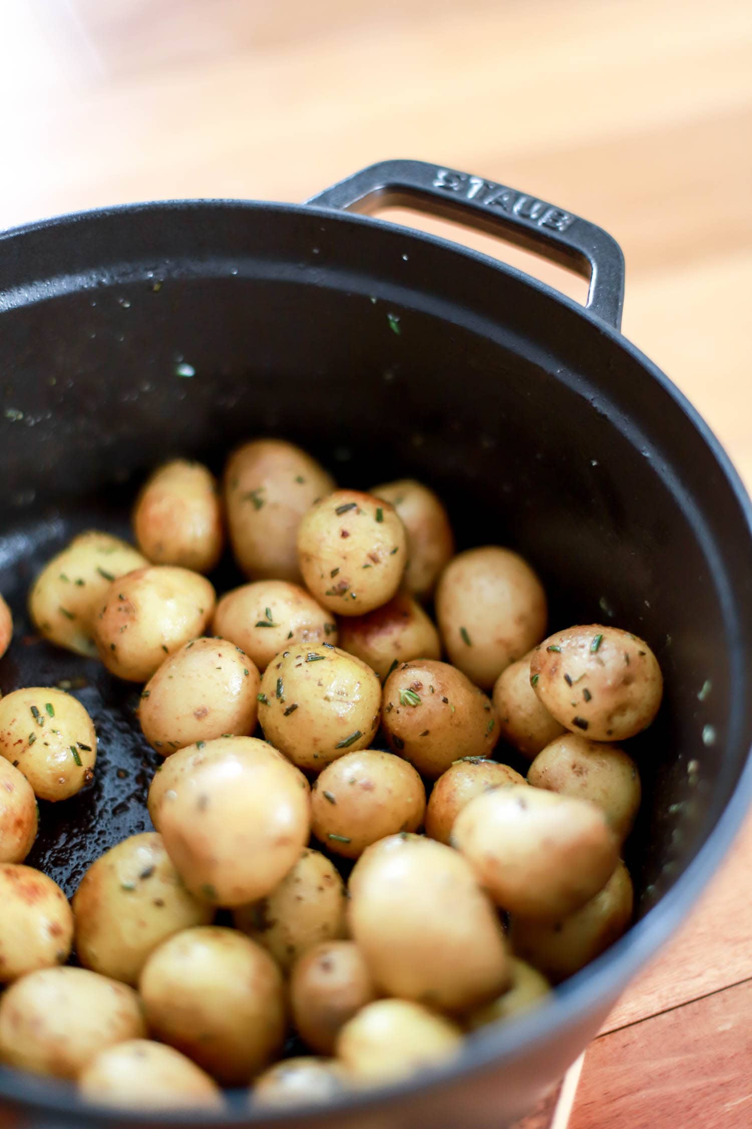 Black pot of tiny steamed potatoes with rosemary.