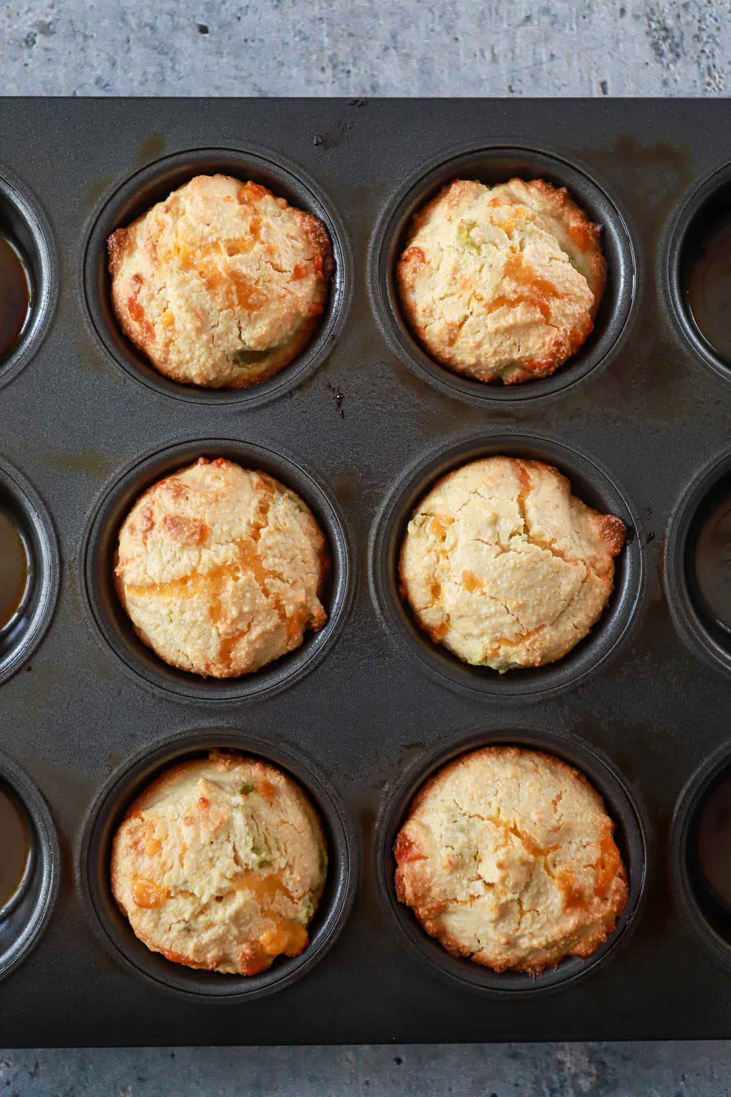 close up of cornbread muffins in black nonstick muffin pan.