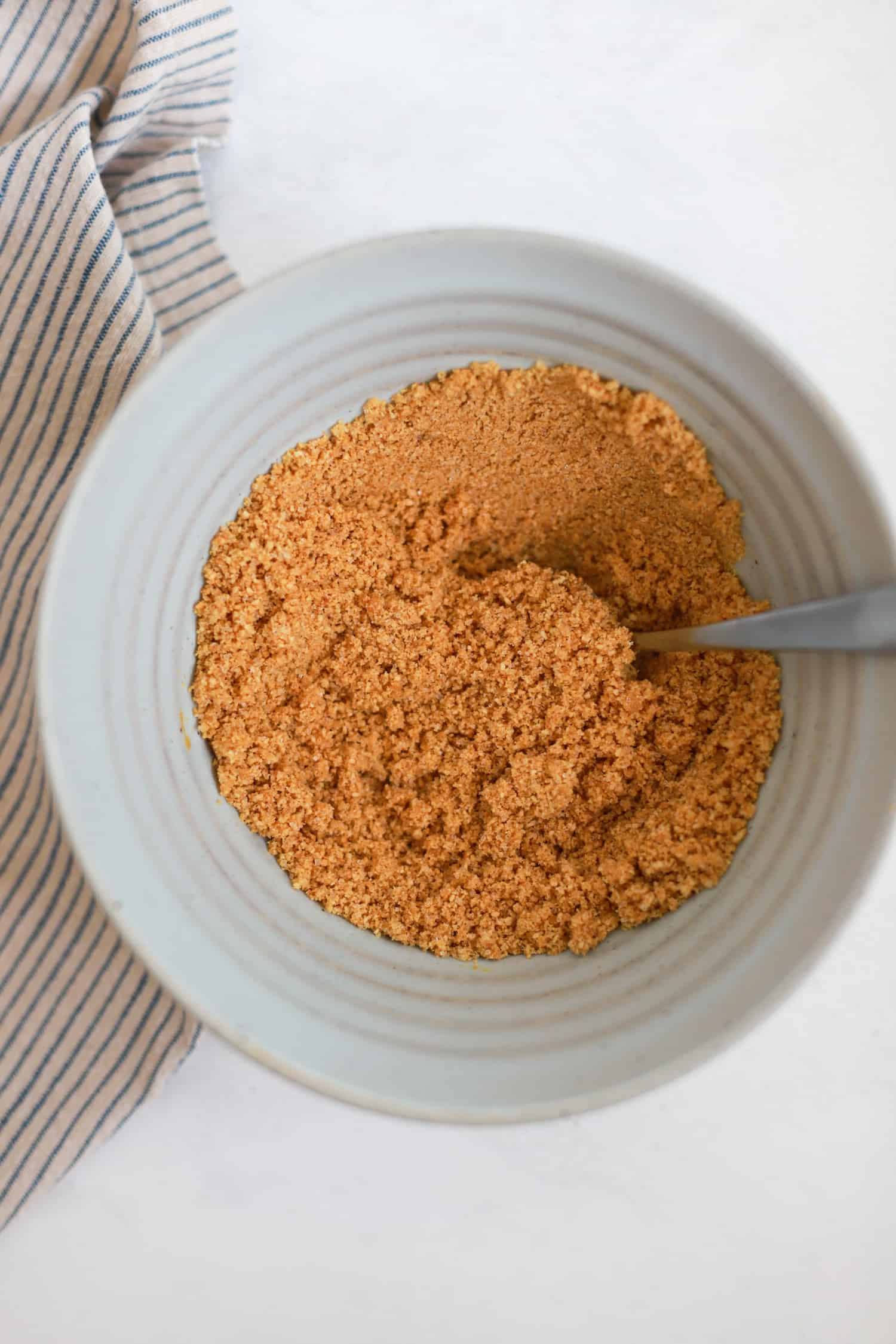 Ingredients for graham cracker crust in a ceramic mixing bowl.
