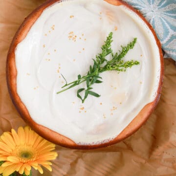 Top view of sour cream cheesecake decorated with fresh flowers.
