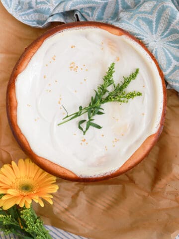 Top view of sour cream cheesecake decorated with fresh flowers.