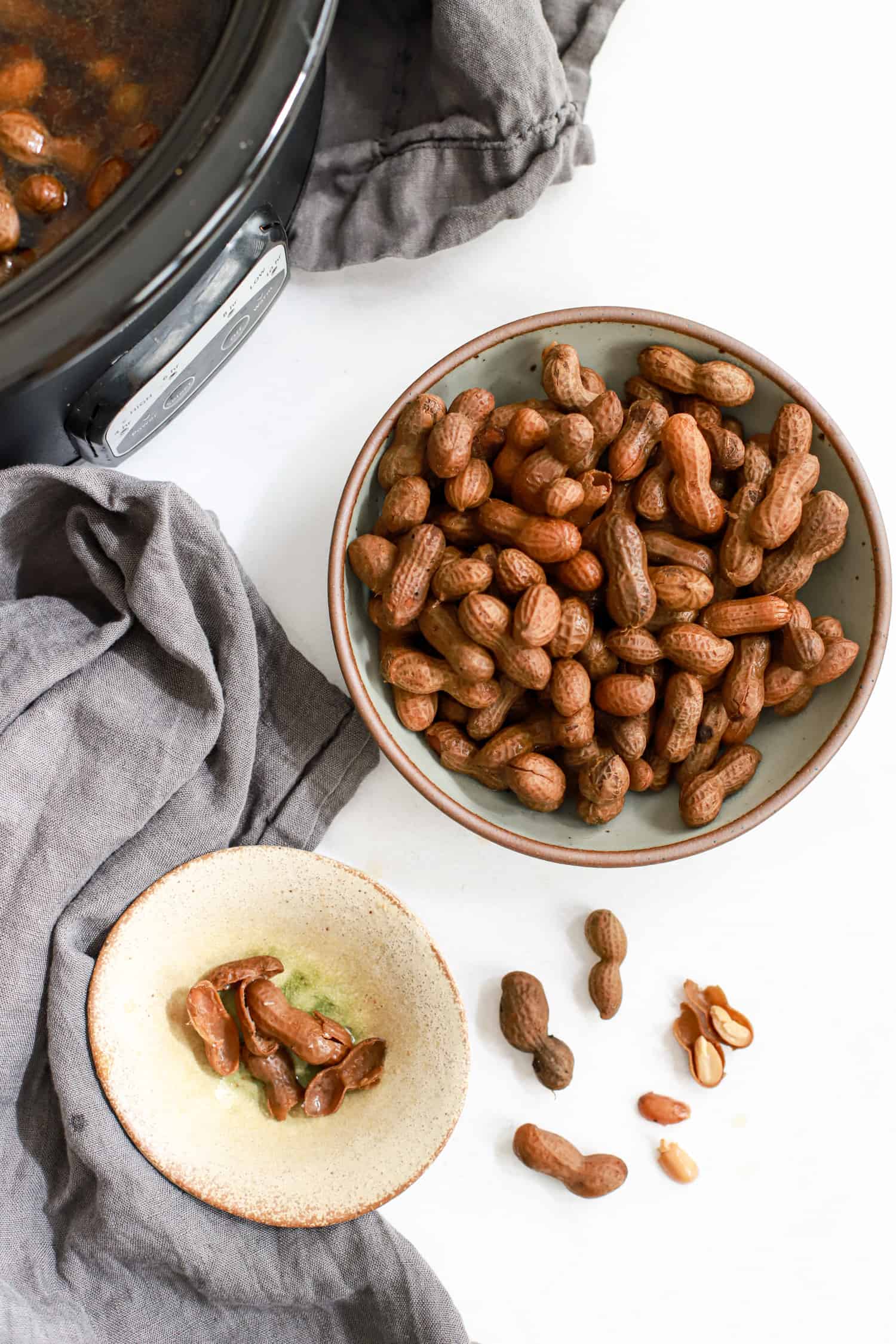 Top view of bowl of boiled peanuts with small dish for discarding shells.