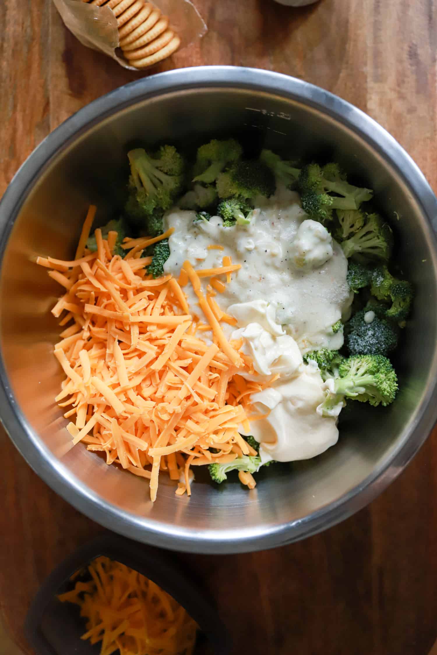silver bowl with ingredients for broccoli cheddar casserole.