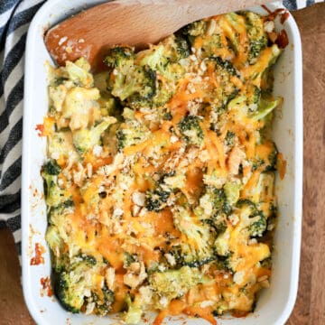 white baking dish with broccoli casserole and wooden spoon.