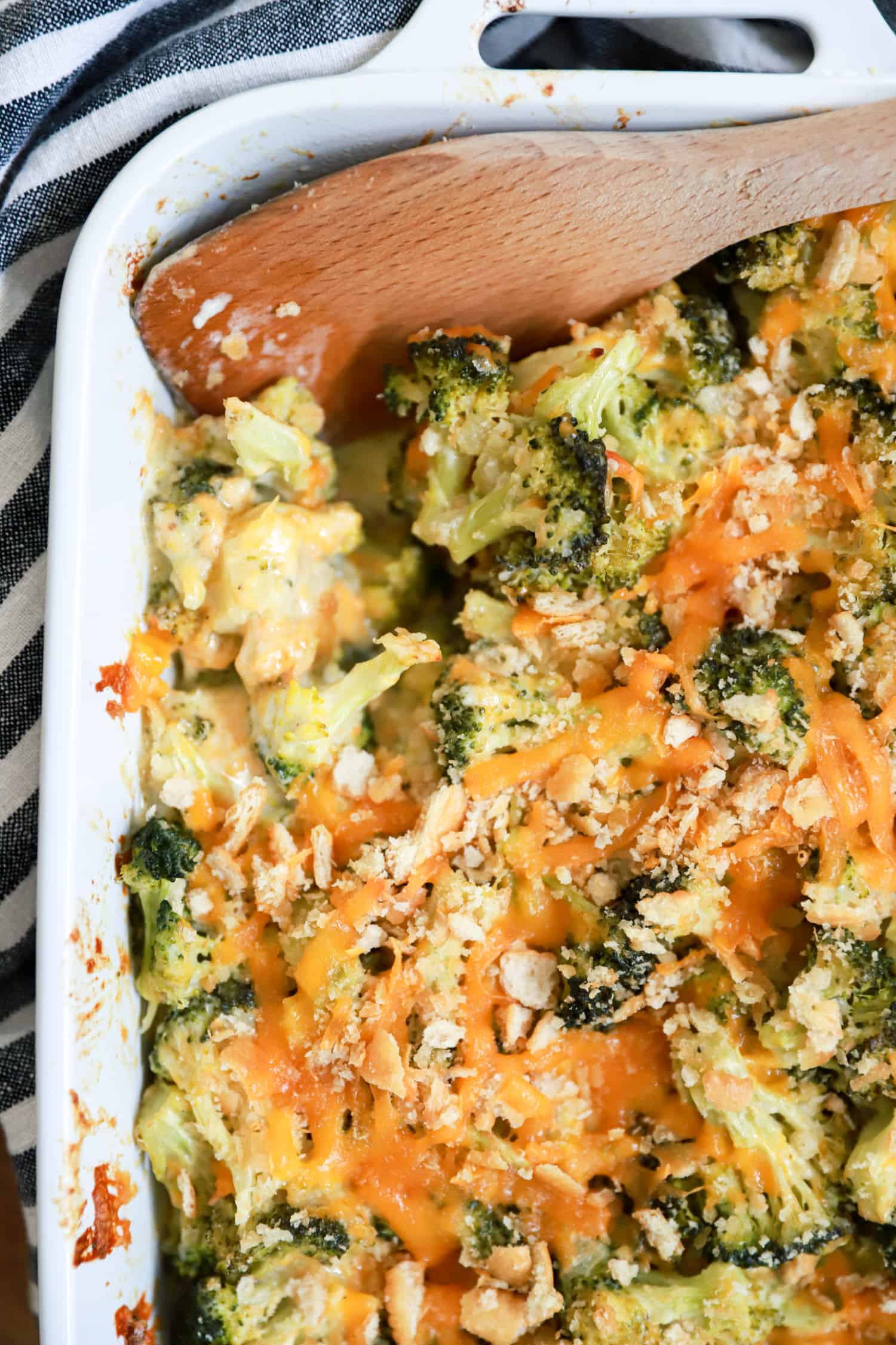 broccoli casserole with ritz crackers and mayonnaise in white baking dish.