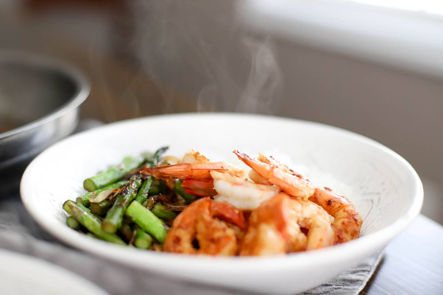 steaming bowl of shrimp and vegetables with steam in the background.
