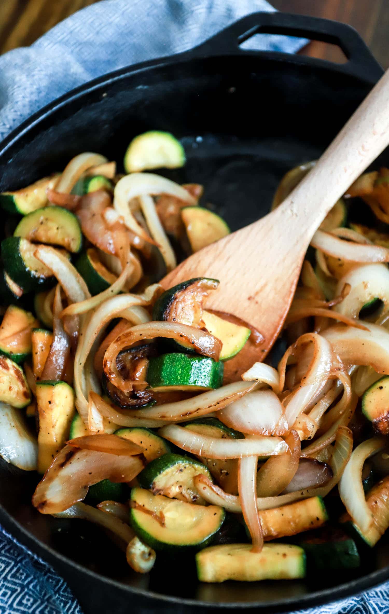 sauteed zucchini and onions with wooden spoon in cast iron skillet.