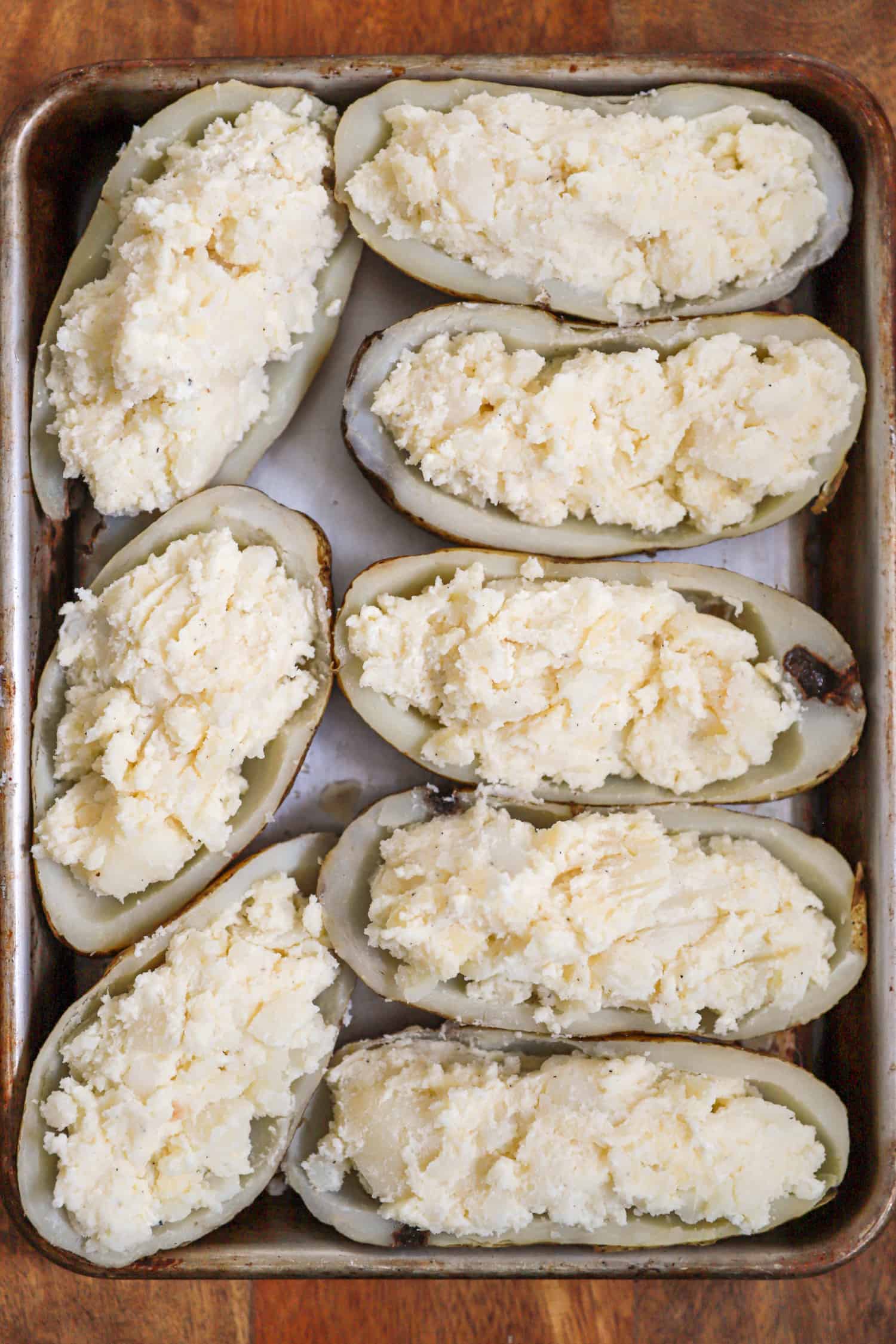 Twice baked potatoes before baking on a silver baking sheet.