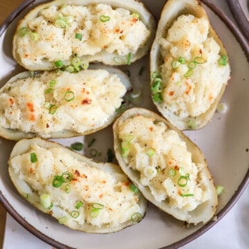 Large serving platter of twice baked potatoes topped with green onions.