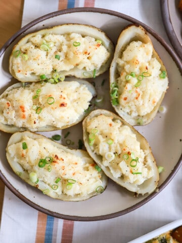 Large serving platter of twice baked potatoes topped with green onions.