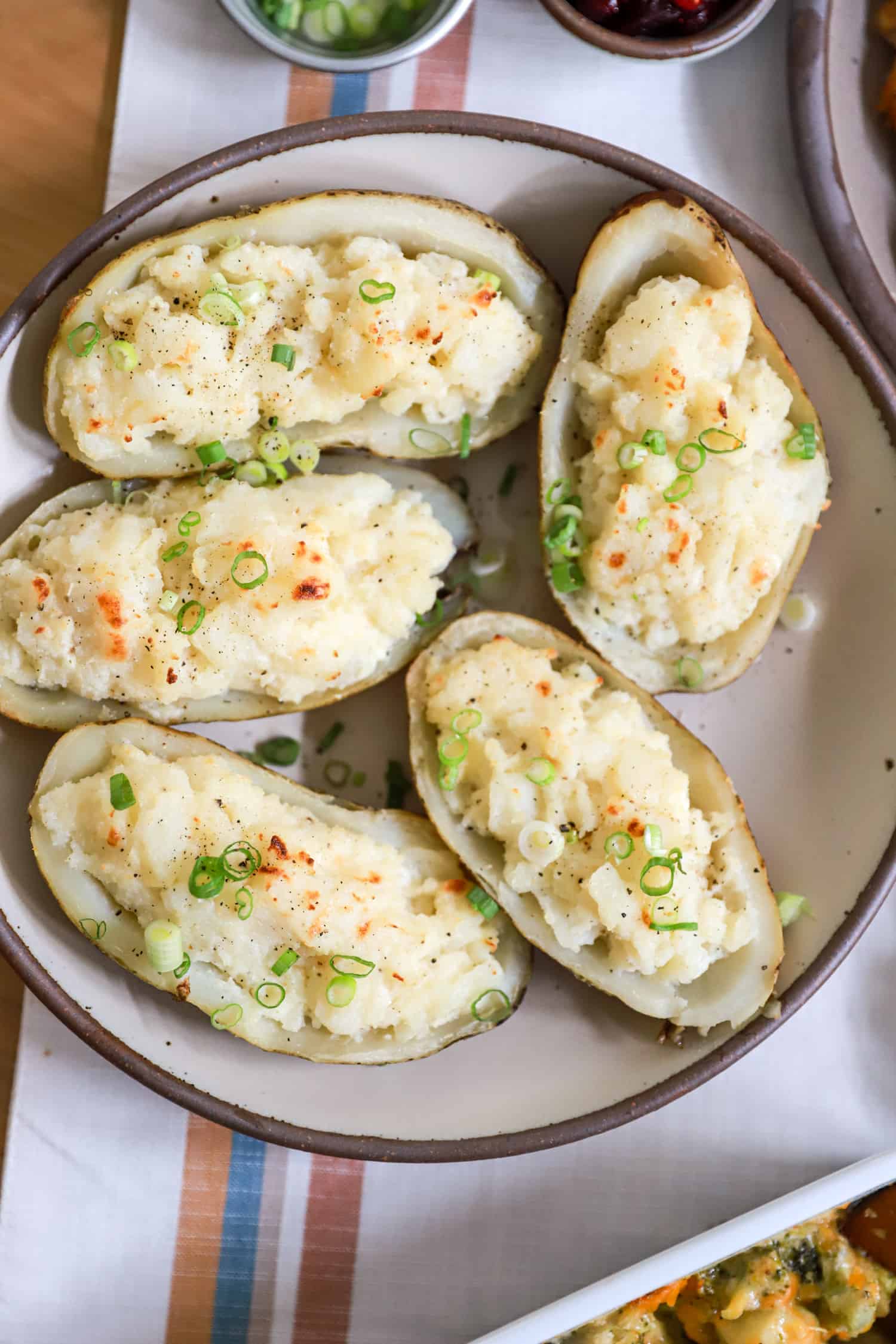 Large serving platter of twice baked potatoes topped with green onions.