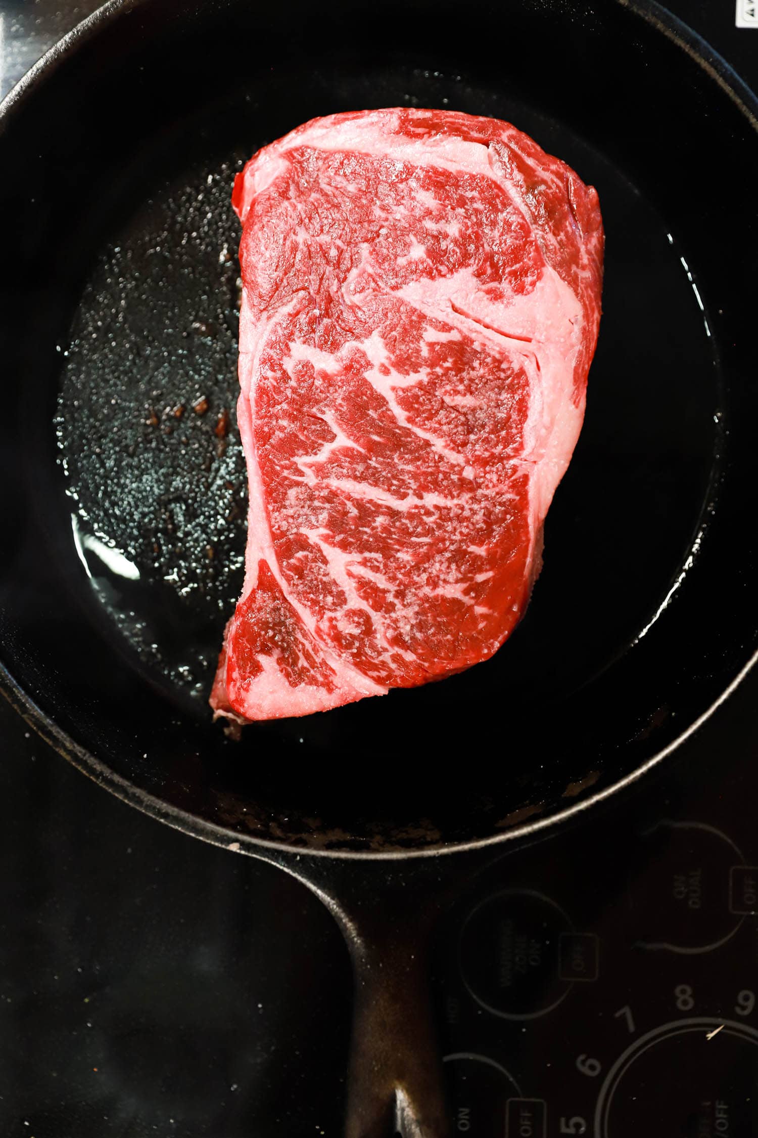 Ribeye steak in a black skillet.