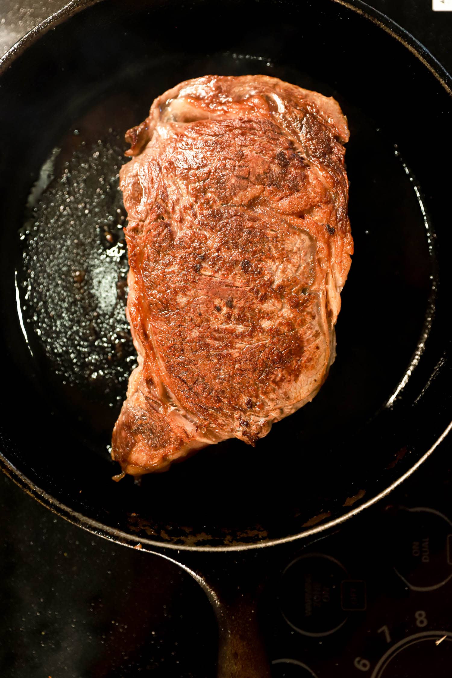 Seared ribeye steak in a cast iron skillet pan.