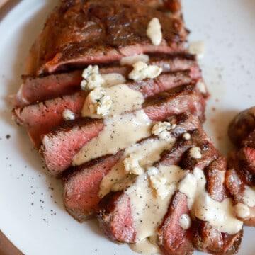 Thickly sliced rare steak with blue cheese sauce drizzled over top.