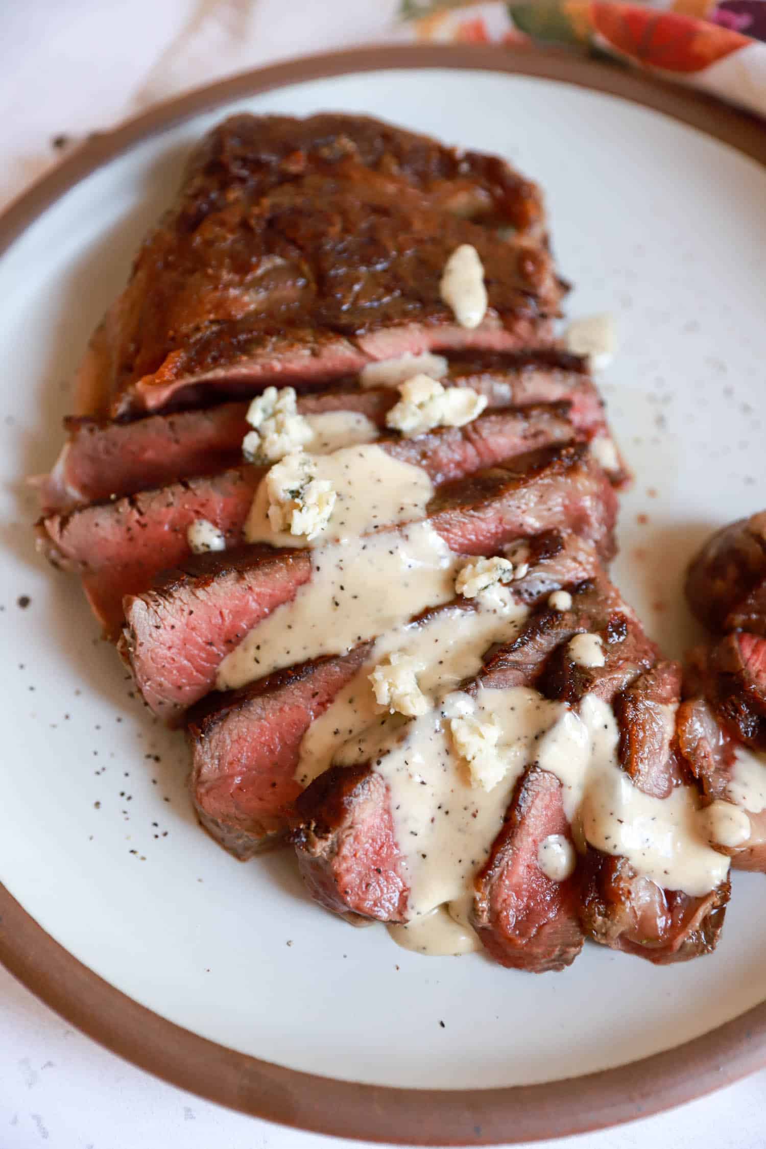 Thickly sliced rare steak with blue cheese sauce drizzled over top.