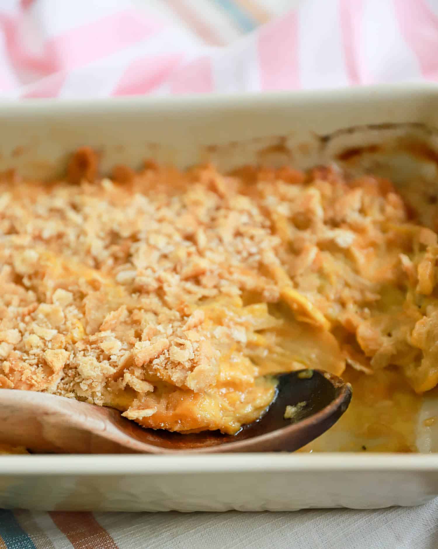 Side view of squash casserole with wooden spoon.