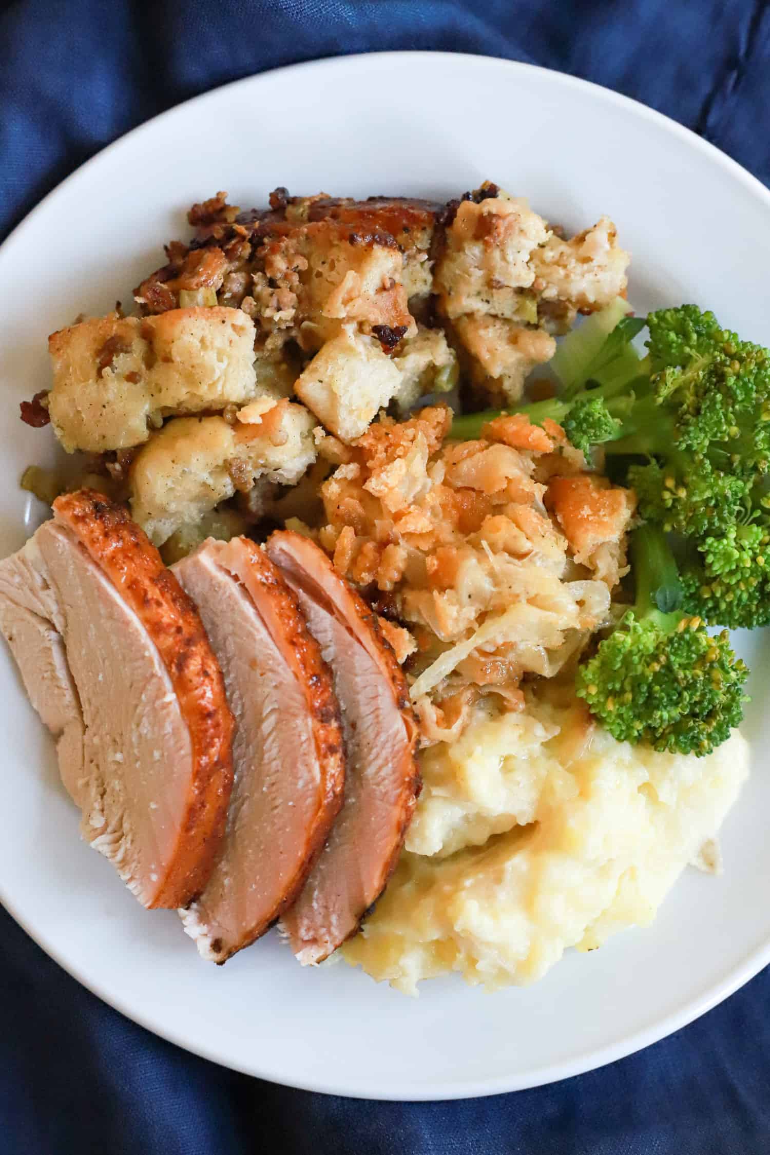 thanksgiving plate with stuffing, onion casserole, broccoli, and sliced turkey.