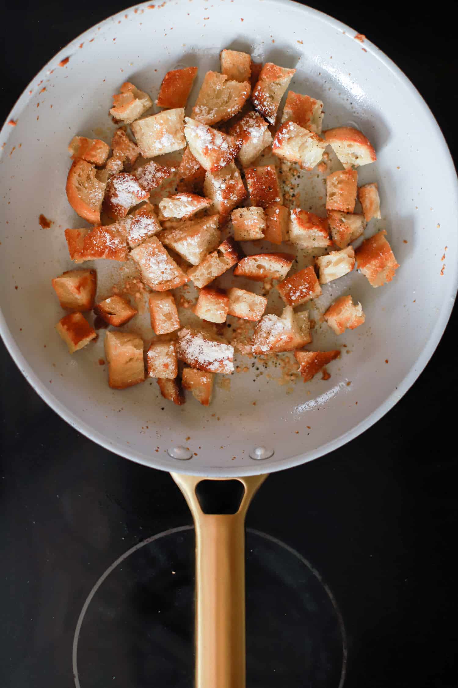 white ceramic skillet with toasted bread cubes for croutons.