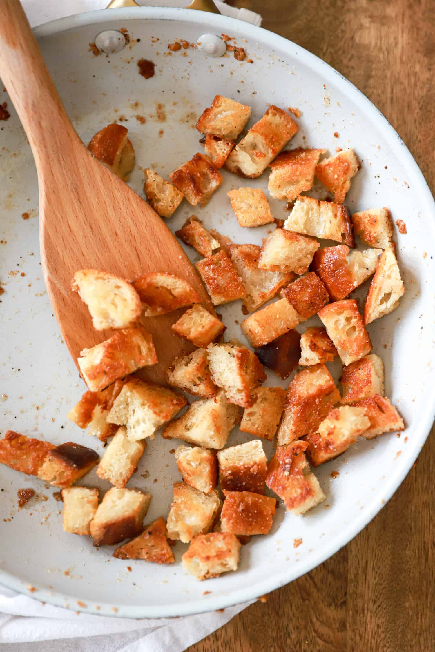 close up top view of homemade croutons in a white skillet.