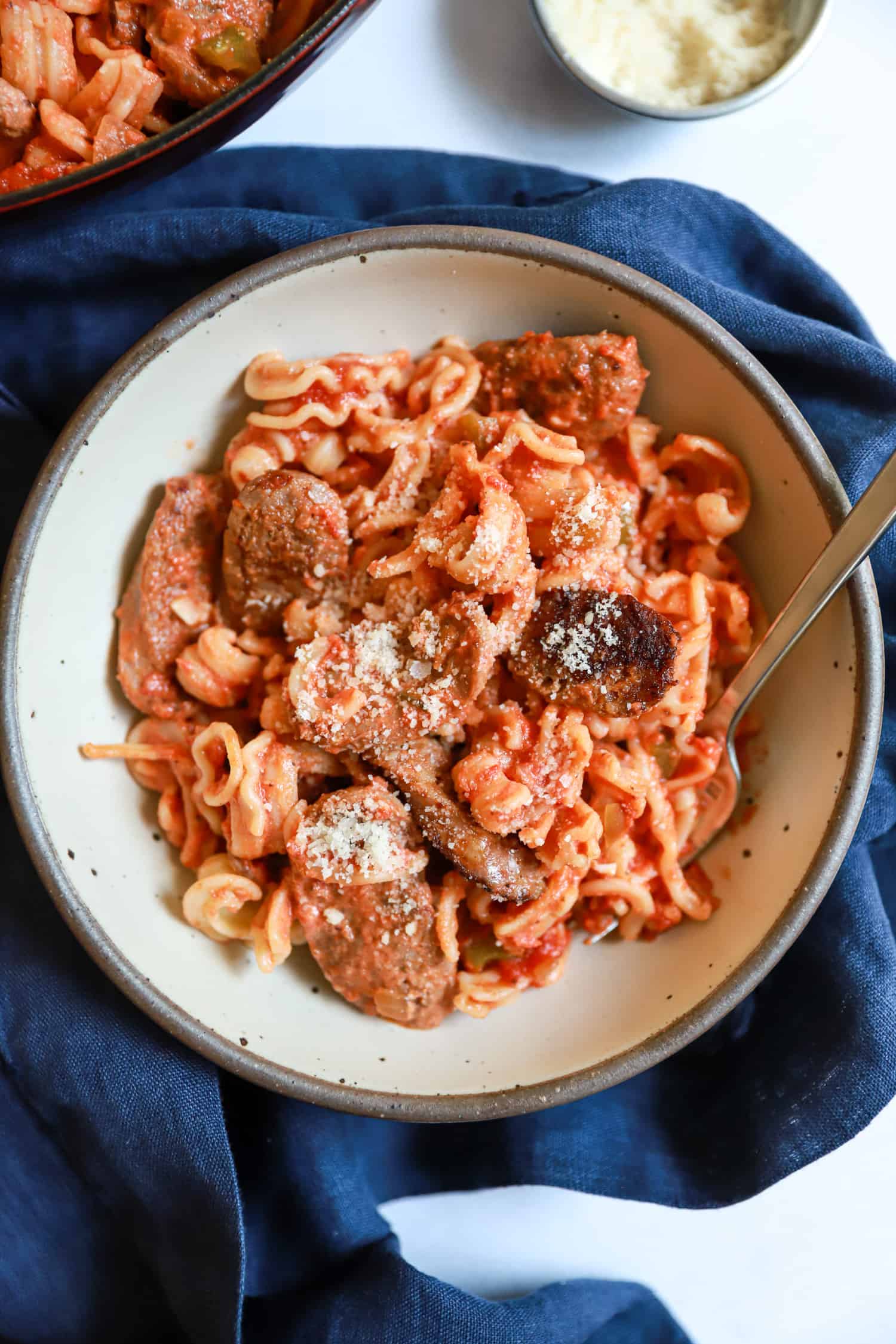 tan bowl of sausage, peppers, onions.