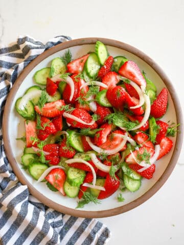 Serving dish of strawberry cucumber salad with pickled white onions.