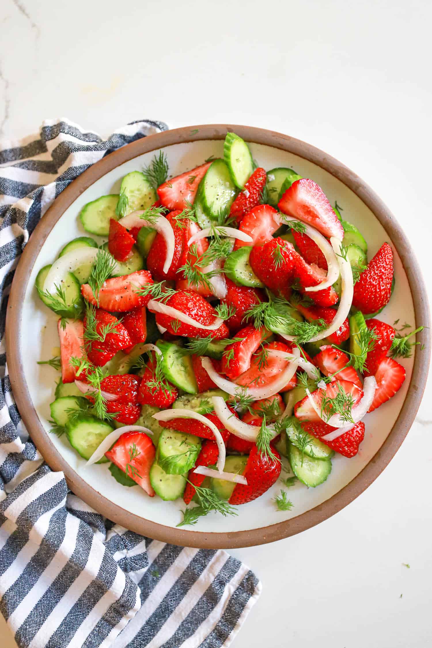Serving dish of strawberry cucumber salad with pickled white onions.