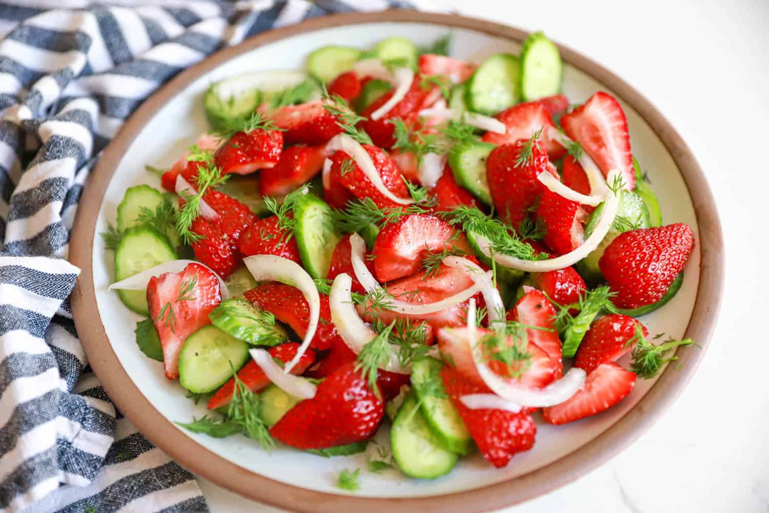 Ceramic plate of cucumber and strawberry salad.