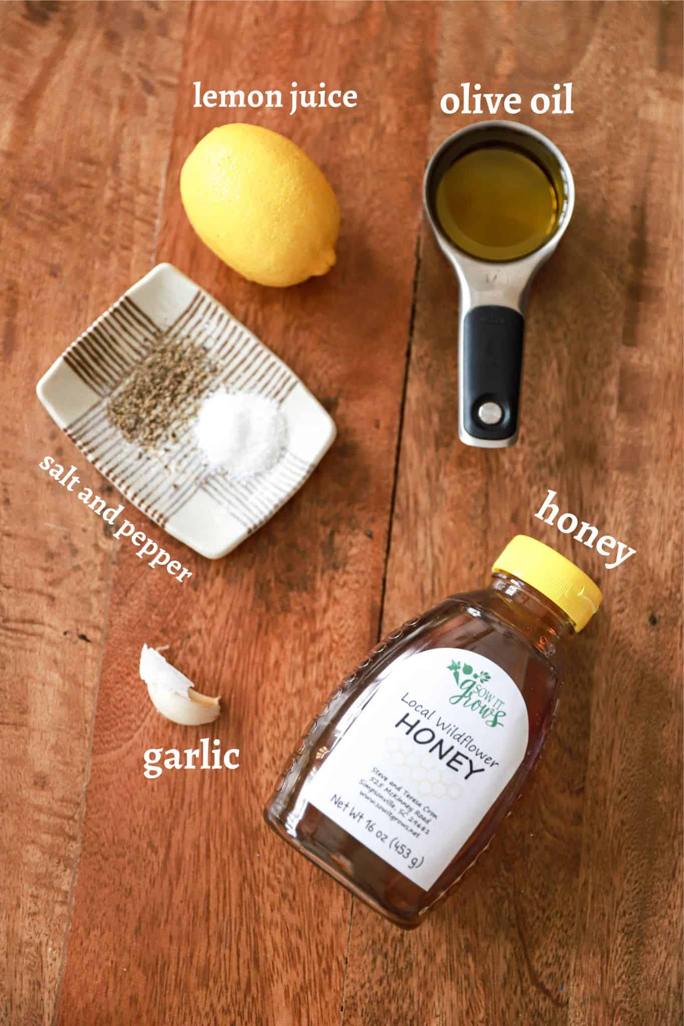 Ingredients for honey lemon vinaigrette on a wooden board.