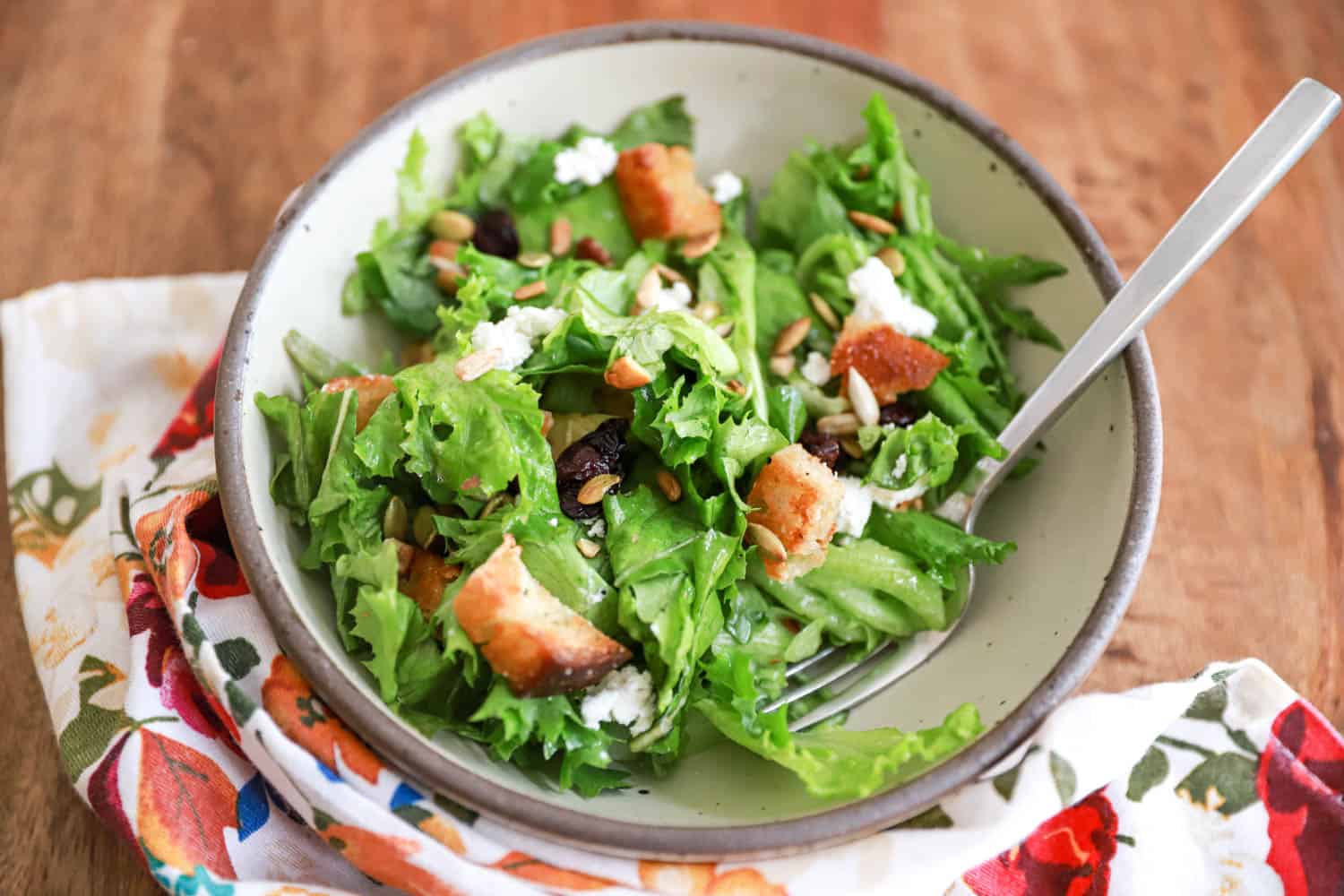 gray bowl of homemade house salad with croutons and goat cheese.