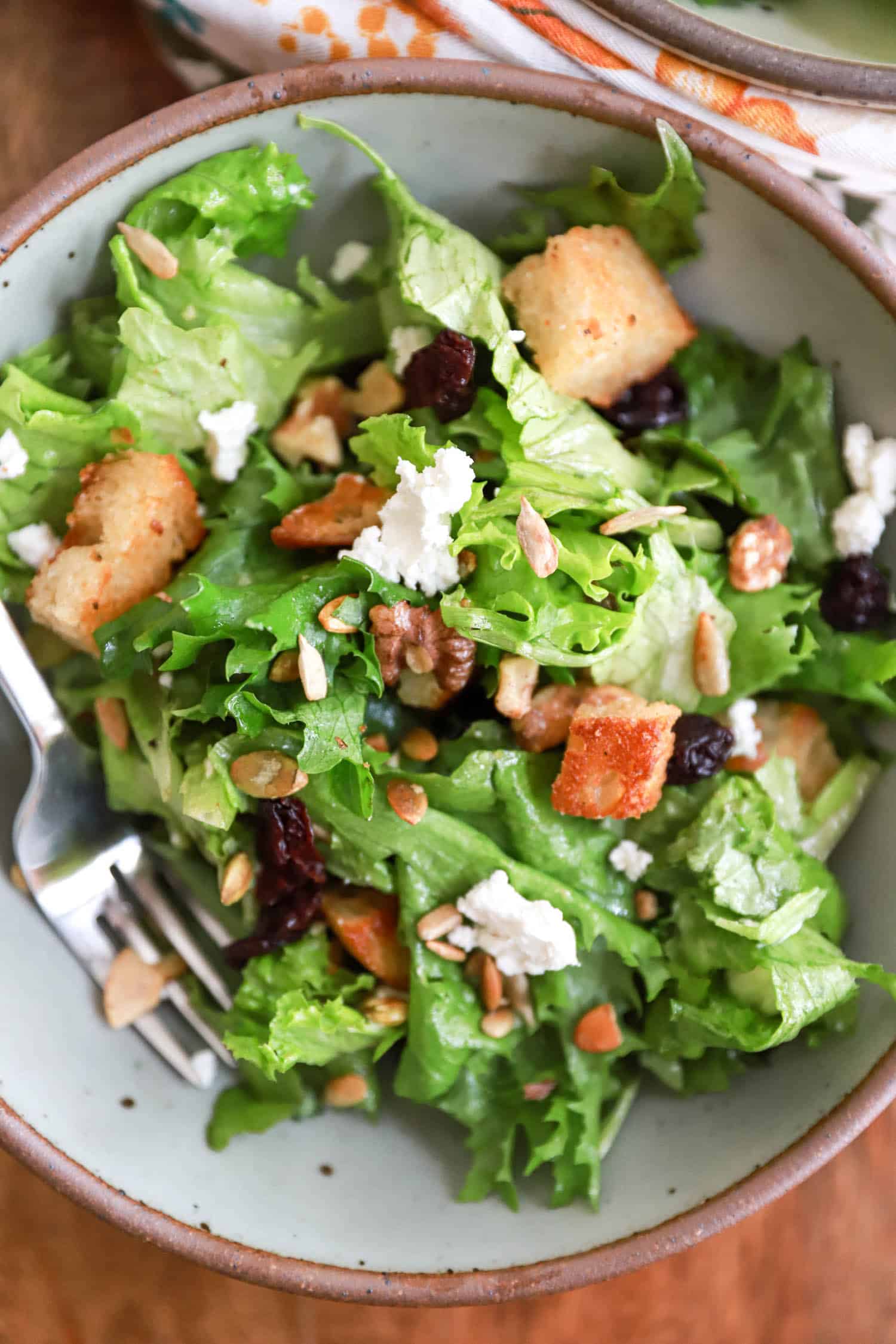 Gray bowl of salad with croutons and goat cheese.