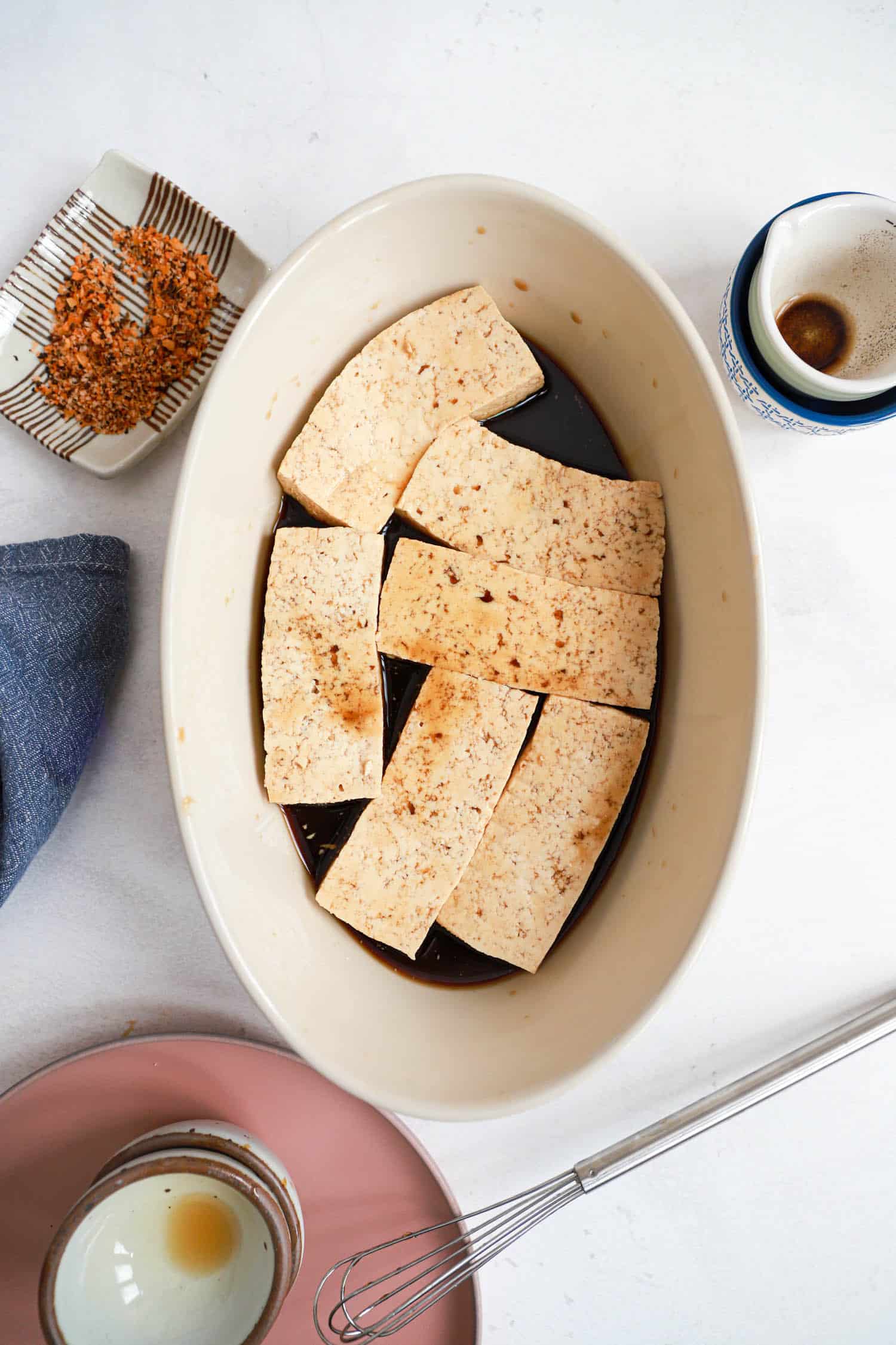 Oval dish with marinating tofu slabs.