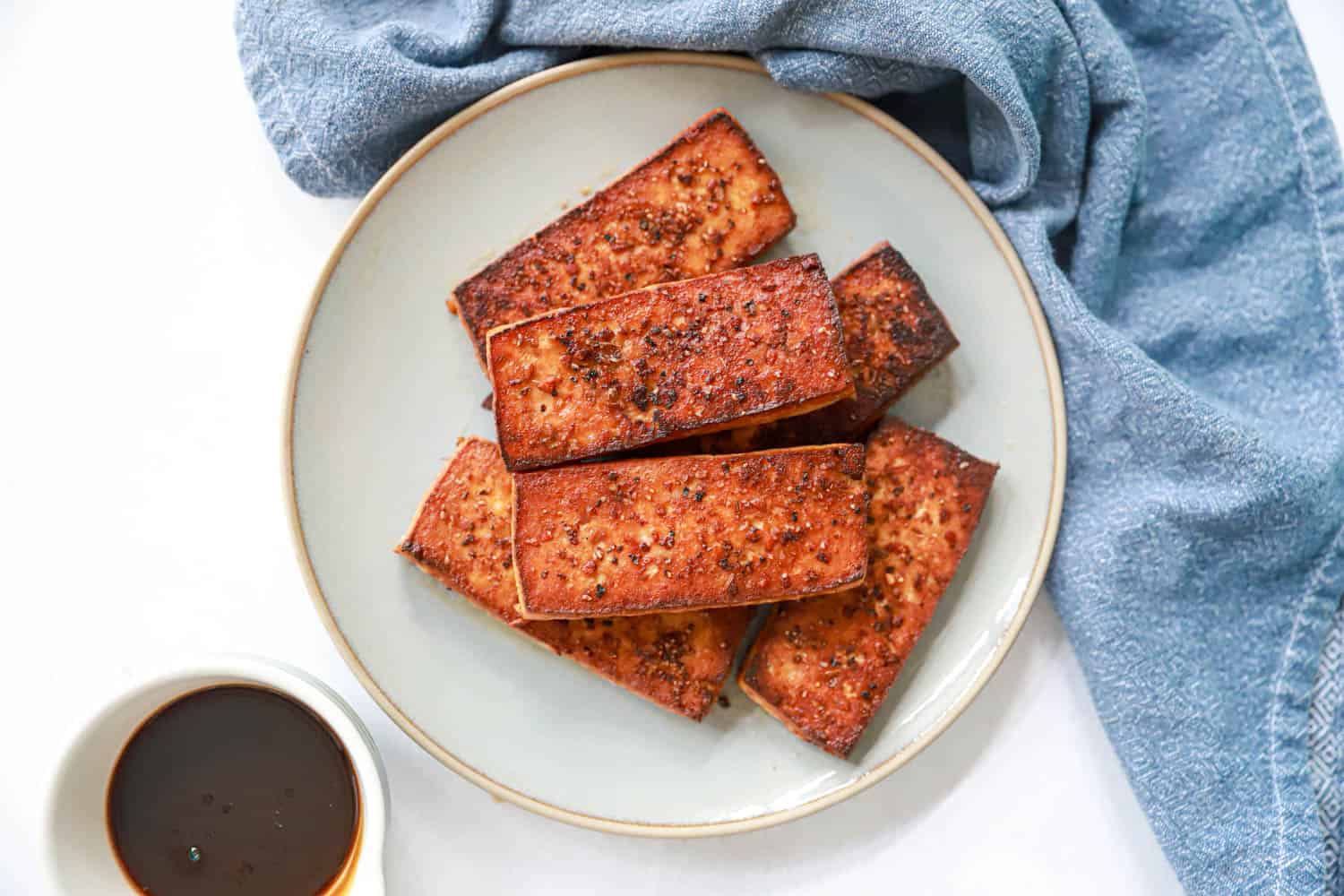 Tofu Steak slabs on grey plate with homemade tofu steak sauce.