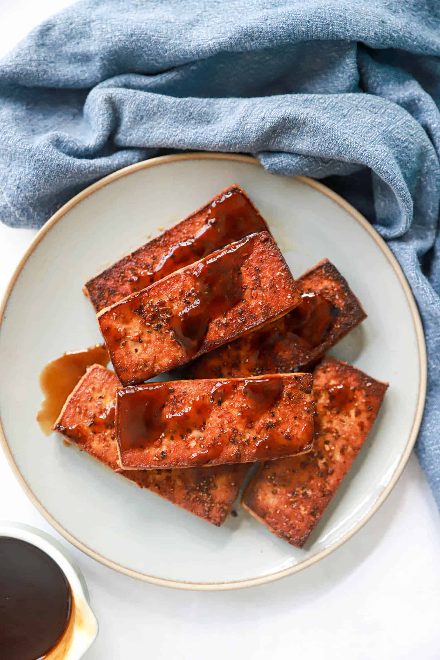 Gray plate of tofu steaks drizzled with steak sauce.