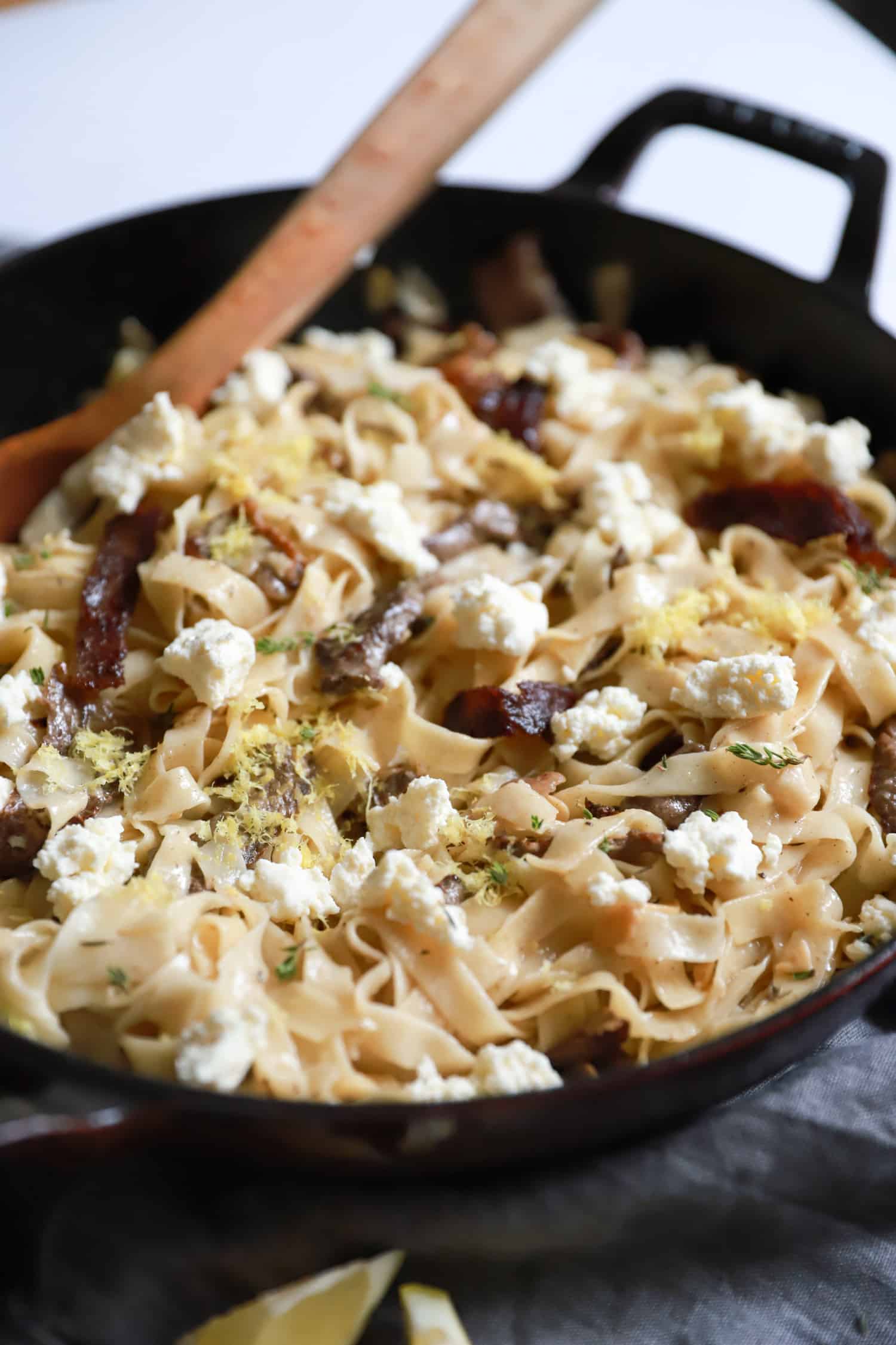 skillet with steak tagliatelle topped with ricotta.