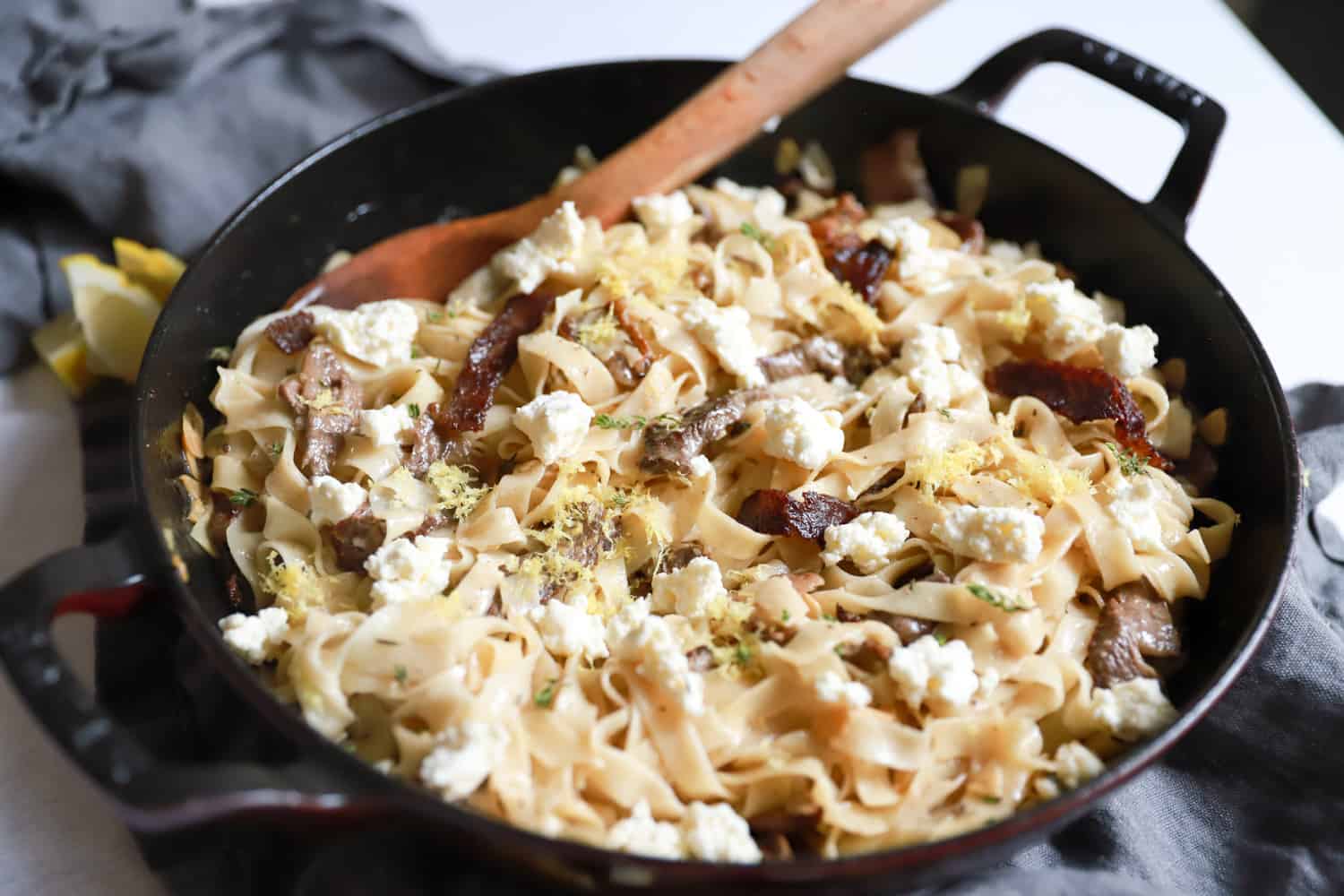 Large black pan of steak ricotta pasta with lemon zest.