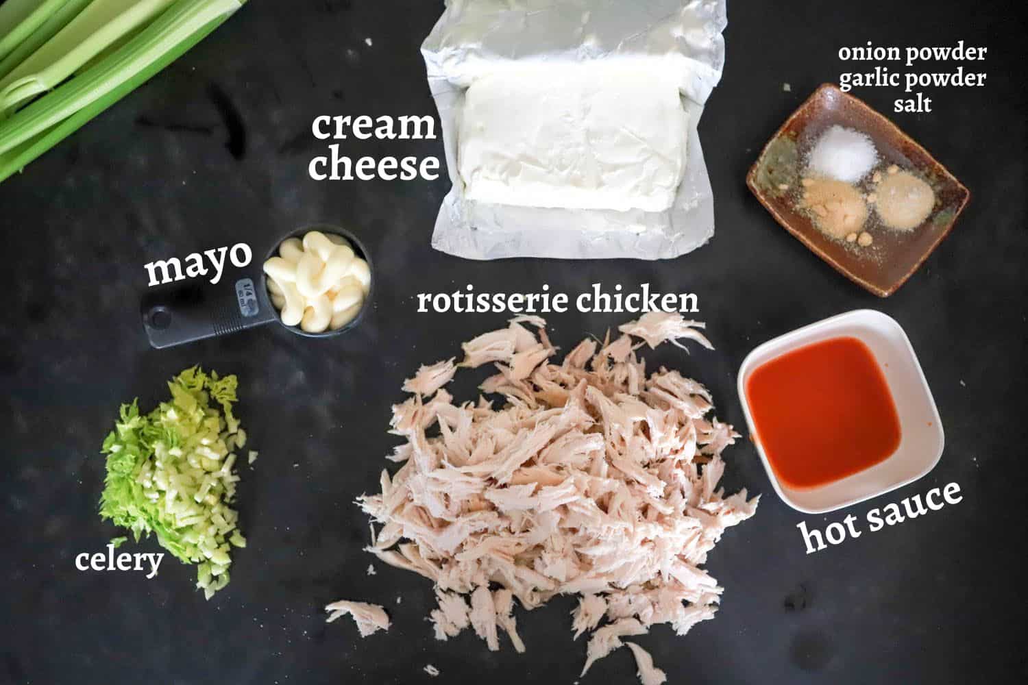 ingredients for cold buffalo chicken dip on black board.