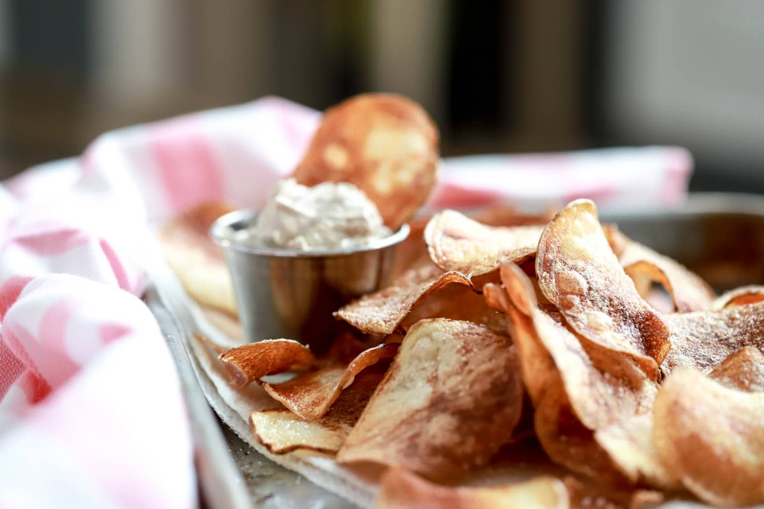 pan fried potato chips pile with french onion dip in the background.