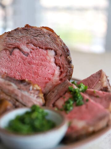 side view of cut prime rib served with chimichurri.