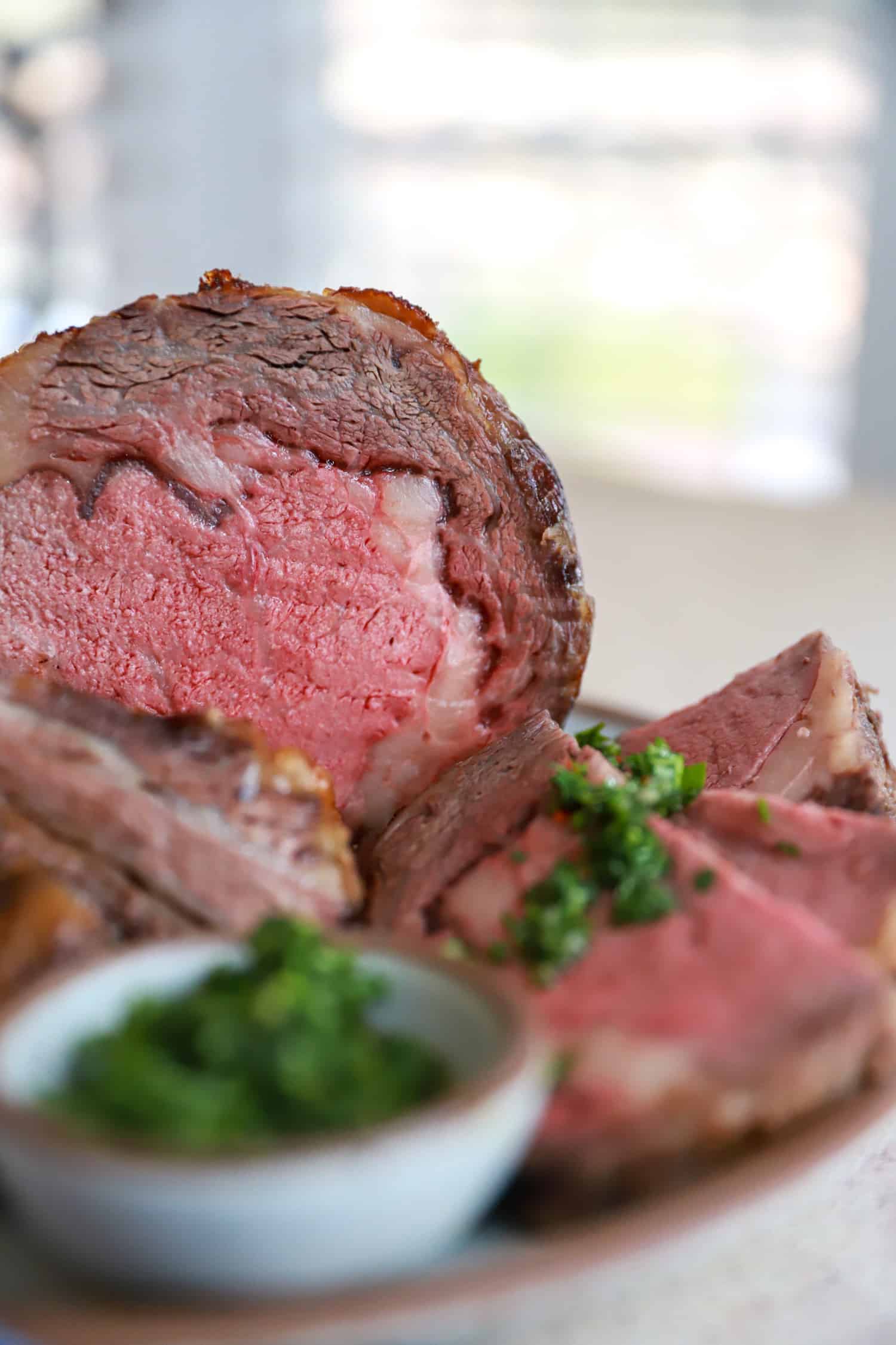 side view of cut prime rib served with chimichurri.