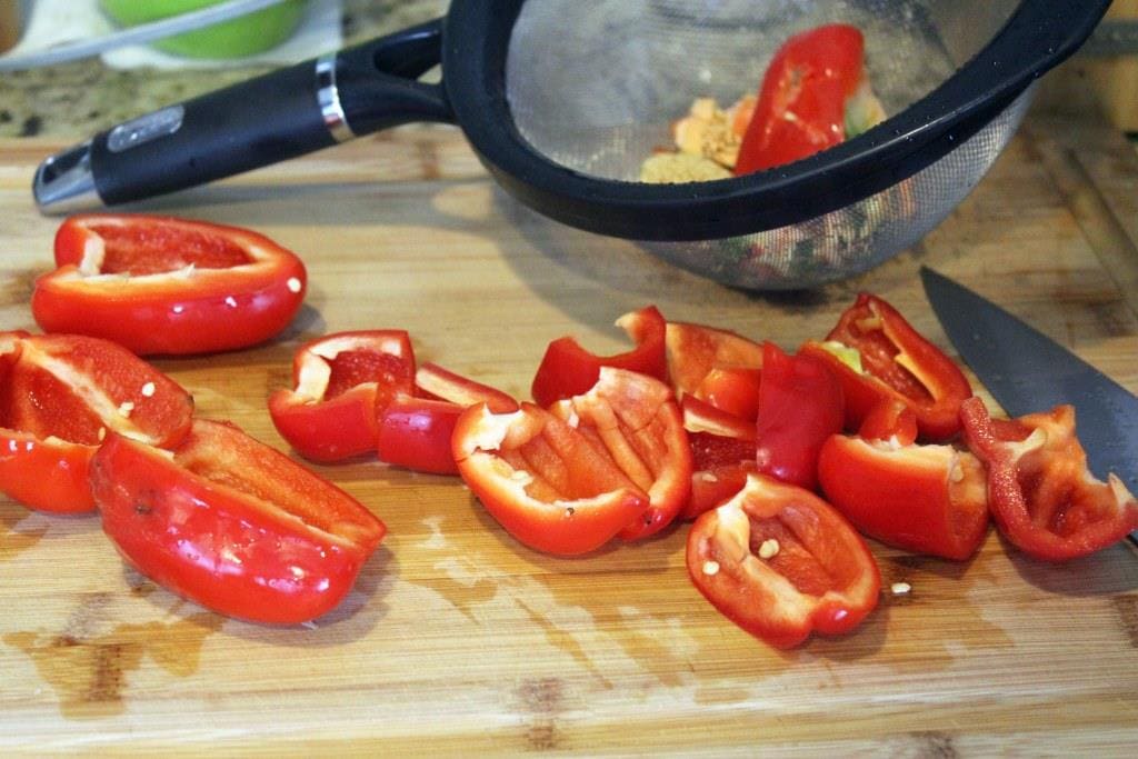 cut up red bell peppers on light wood cutting board.