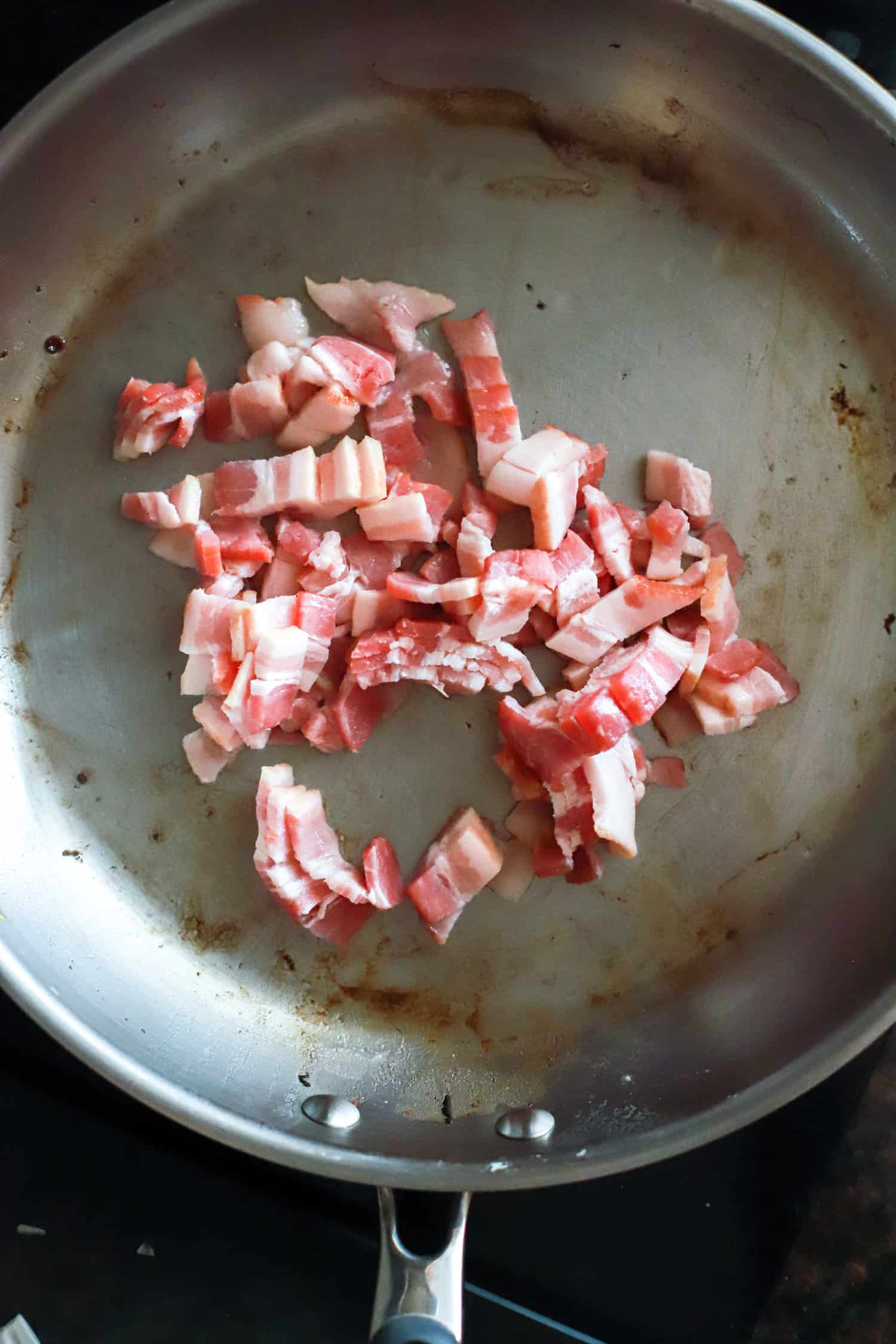 Raw bacon in large skillet before frying.